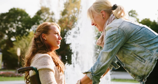 Personlig assistent som hjälper rullstolsbunden kvinna